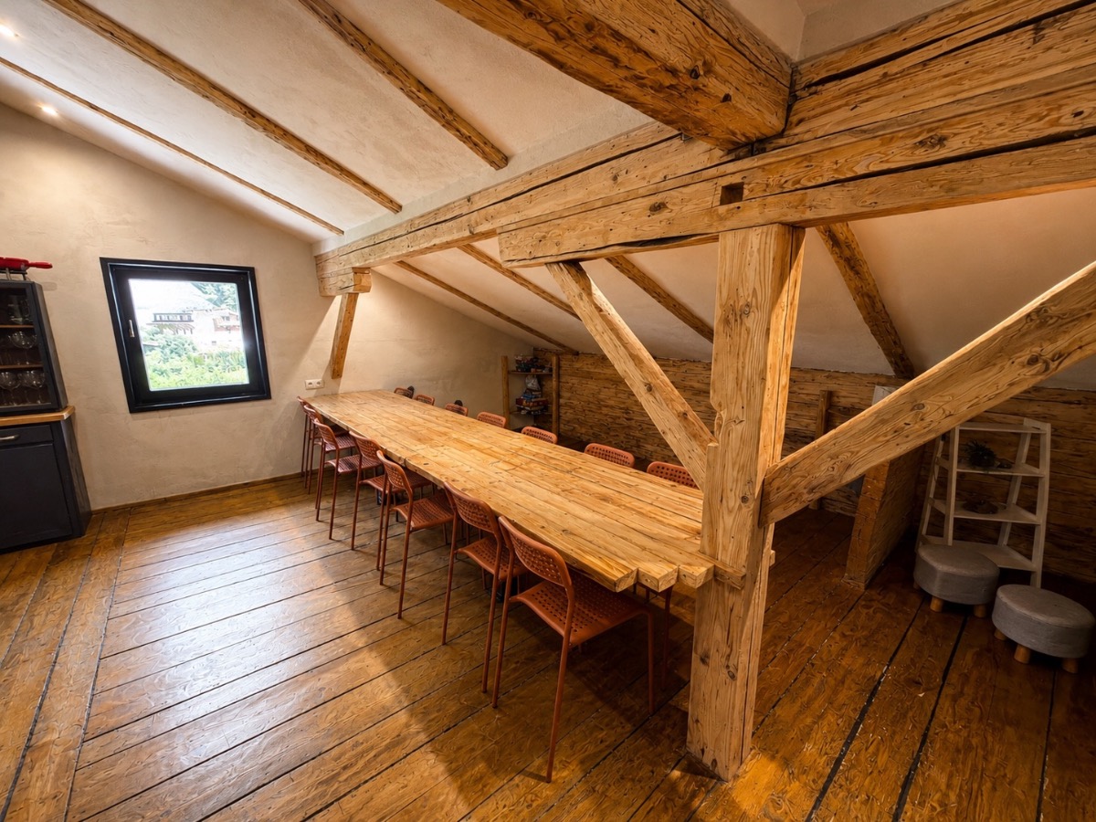 The long shared dining table under exposed wooden beams